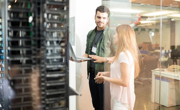 Ein Mann und eine Frau sprechen in einem Serverraum miteinander.