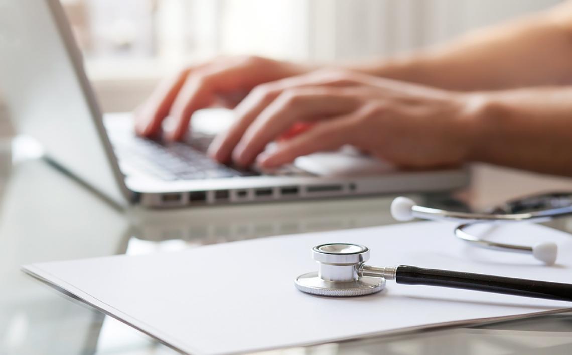 Zwei Hände tippen auf einem Laptop