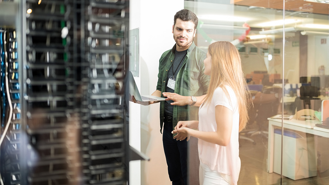 Ein Mann und eine Frau sprechen in einem Serverraum miteinander.