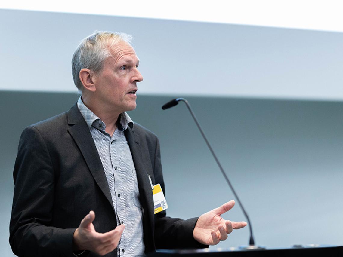 Ein Mann steht an einem Redepult und spricht.