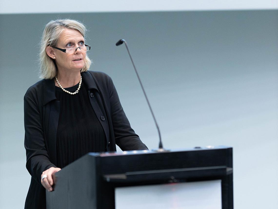 Eine Frau steht an einem Redepult und spricht.