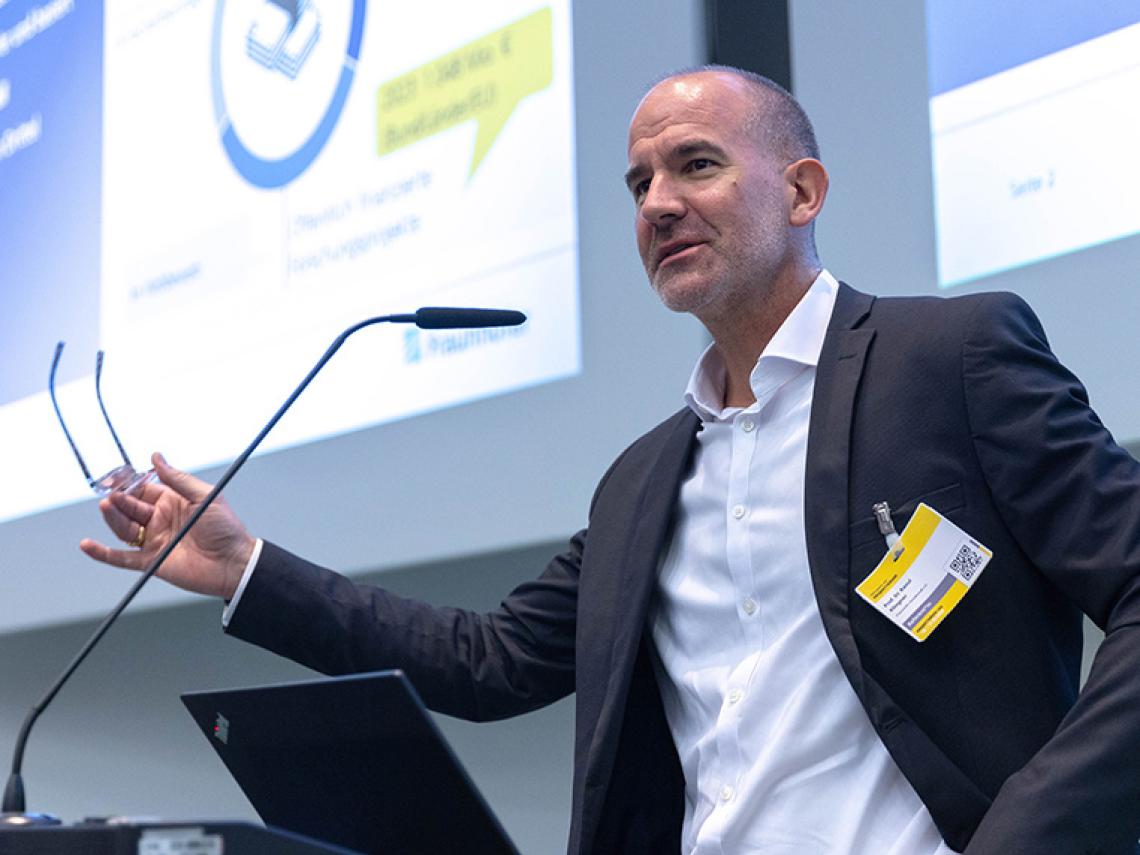 Ein Mann steht an einem Redepult und spricht.