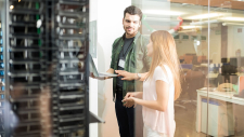 Ein Mann und eine Frau unterhalten sich in einem Server-Raum.